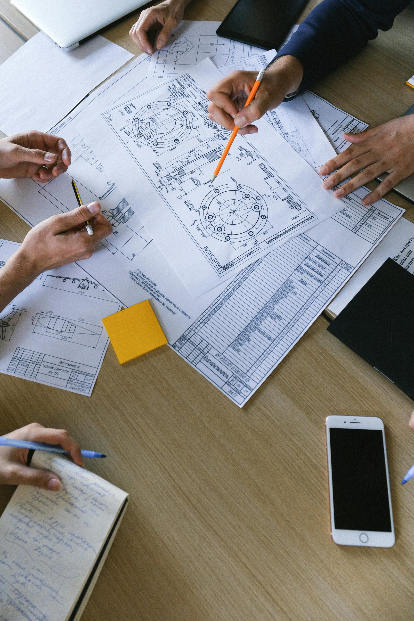 Top view of engineers collaborating on plans with documents and smartphones in an office setting.
